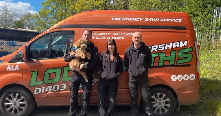 one woman and two men, one of which is holding a dog, standing in front of an orange Horsham Locksmiths van