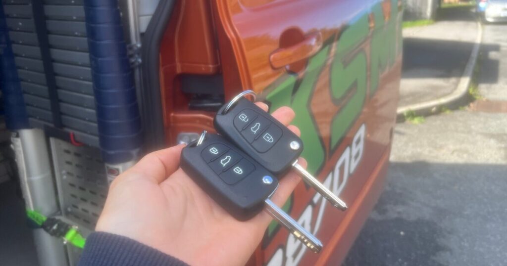 spare car keys held up in front of van