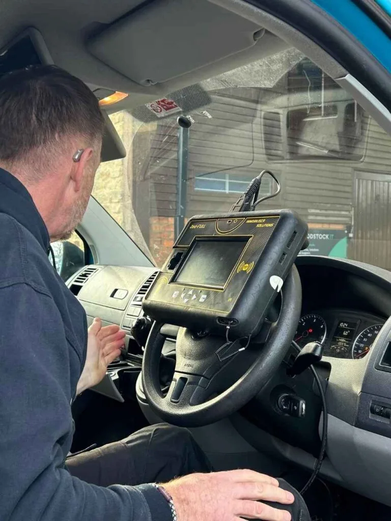 Locksmith in the driver seat of van, programming a key